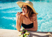 Thumbnail 72 of 75 - a woman in a hat and sunglasses eating fruit at the edge of a pool