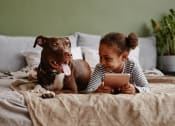 Thumbnail 43 of 52 - a girl and her dog laying on a bed looking at a tablet at North Grove, Riverside, 92501  