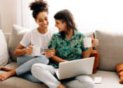 Thumbnail 50 of 52 - two women sitting on a couch drinking coffee while using a laptop computer at North Grove, Riverside, CA  