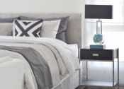 Thumbnail 27 of 80 - a bedroom with a bed and a nightstand with a lamp and a vase on it