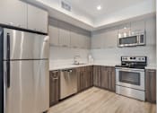 Thumbnail 3 of 26 - A modern kitchen with stainless steel appliances and wooden cabinets at Wilshire Valencia Apartment, Los Angeles, CA, 90017