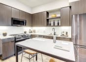 Thumbnail 2 of 18 - Modern Apartments For Rent in Downtown Oakland, CA - Edson House - Kitchen With Slate Appliances With Natural Gas Range, Tile Backsplash, Luxury Wood Finish Plank Flooring, and Quartz Countertops.