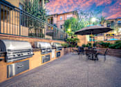 Thumbnail 50 of 80 - A patio with a table and chairs and a grill.