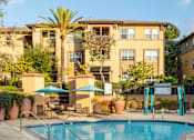 Thumbnail 67 of 80 - A swimming pool surrounded by a patio with chairs and umbrellas.