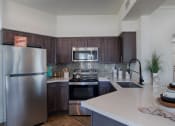 Thumbnail 20 of 39 - Kitchen With Dark Wood Cabinets, White Countertops, Grey Backsplash, And Appliances at McDermott Place, Plano, TX