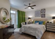 Thumbnail 16 of 39 - Bedroom With Wood-style Flooring, A Large Window, An Exterior Glass Door With A Small Window Above, A Ceiling Fan, And Bedroom Furniture at McDermott Place, Plano, Texas
