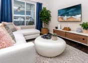 Thumbnail 63 of 78 - a living room with a white couch and a coffee table and a television at Miro at the Parc, Henderson, NV