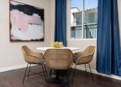 Thumbnail 64 of 78 - a dining area with a table and chairs and a window with blue curtains at Miro at the Parc, Henderson, 89074