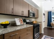 Thumbnail 60 of 78 - a kitchen with wooden cabinets and stainless steel appliances and granite counter tops at Miro at the Parc, Nevada