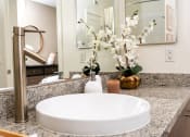 Thumbnail 71 of 78 - a bathroom sink with a mirror and a vase of flowers at Miro at the Parc, Henderson, 89074