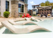 Thumbnail 19 of 78 - commons pool and hot tub with chairs and a building at Miro at the Parc, Henderson, Nevada
