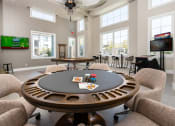 Thumbnail 1 of 78 - a poker table in a clubhouse with chairs and a tv at Miro at the Parc, Henderson, NV 89074