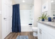 Thumbnail 22 of 36 - a bathroom with white cabinets and a blue shower curtain at Montrachet Apartments, Napa, CA