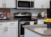 Thumbnail 20 of 33 - A kitchen with white cabinets and a black stove top oven.