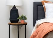 Thumbnail 57 of 67 - a bedroom with a bed and a table with a lamp and a plant