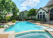 Thumbnail 8 of 40 - A large swimming pool surrounded by a black fence and a green house in the background.