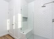 Thumbnail 14 of 44 - A white tiled bathroom with a walk-in shower. at Nola 624, West Covina California