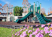 Thumbnail 37 of 44 - A playground with a green slide and purple flowers in the foreground. at Nola 624, West Covina