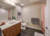 Thumbnail 19 of 24 - A Bathroom With Luxury Plank Flooring, Large Vanity Mirror, Sink With Wood-Inspired Cabinets, Toilet, And A Shower With Tub. at NoMa Apartments, California, 94596