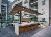 Thumbnail 5 of 24 - a patio with a bar and a large building in the background at NoMa Apartments, California