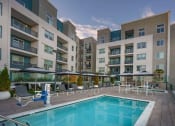 Thumbnail 7 of 24 - Resort-Style Pool and Spa with Lounge Chairs and View of Building Exterior at NoMa Apartments, Walnut Creek, CA, 94596