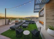 Thumbnail 3 of 24 - A Rooftop Deck With Lounge Chairs, Fireplace, Wall-Mounted TV, Tables, And City Views. at NoMa Apartments, California, 94596