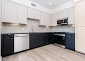 Thumbnail 14 of 52 - A kitchen with black and white cabinets and a microwave above the stove.