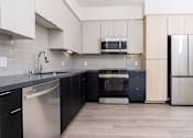 Thumbnail 5 of 52 - A kitchen with black and white appliances and wooden cabinets.