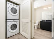 Thumbnail 18 of 52 - A white washing machine and dryer in a small laundry room.