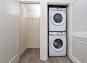 Thumbnail 17 of 52 - A white washing machine is in a small laundry room.