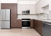 Thumbnail 10 of 52 - A modern kitchen with a refrigerator, oven, microwave, and sink.