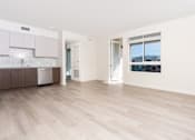Thumbnail 36 of 52 - A spacious room with wooden flooring and a view of buildings outside the window.
