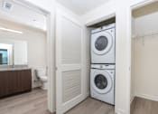 Thumbnail 38 of 52 - A white washer and dryer are stacked on top of each other in a laundry room.
