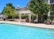 Thumbnail 19 of 39 - A pool with a white pergola and trees in the background at Avalon at Seven Hills Apartments, Henderson, NV, 91790