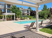 Thumbnail 21 of 39 - A pool surrounded by chairs and a white pergola at Avalon at Seven Hills Apartments, Nevada, 91790