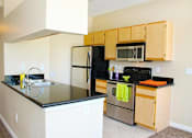Thumbnail 7 of 39 - A kitchen with a black counter top and stainless steel appliances at Avalon at Seven Hills Apartments, Nevada