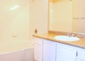 Thumbnail 16 of 39 - A white bathroom with a tub, sink, and mirror at Avalon at Seven Hills Apartments, Henderson