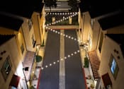 Thumbnail 100 of 112 - A narrow street with buildings on either side is illuminated by string lights.