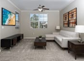 Thumbnail 11 of 112 - A living room with a white couch, a television, and a ceiling fan.