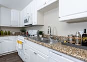 Thumbnail 8 of 112 - A kitchen with white cabinets and a granite countertop.