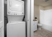 Thumbnail 17 of 112 - A white washing machine is in a small bathroom with a toilet and a sink.