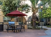 Thumbnail 92 of 112 - A patio with a table and chairs under a red umbrella.