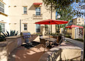 Thumbnail 85 of 112 - A patio with a table and chairs under a red umbrella.