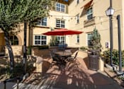 Thumbnail 82 of 112 - A patio with a table and chairs under a red umbrella.