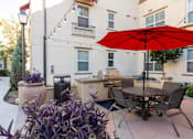 Thumbnail 83 of 112 - A patio with a table and chairs under a red umbrella.