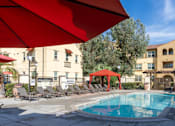 Thumbnail 3 of 112 - A pool area with a red umbrella and lounge chairs.