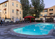 Thumbnail 42 of 112 - A swimming pool surrounded by lounge chairs and umbrellas in front of a building.