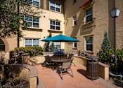 Thumbnail 50 of 123 - a patio with a table umbrella and chairs in front of Paseos at Magnolia