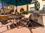 Thumbnail 57 of 123 - a patio with a grill and a table with chairs and an umbrella