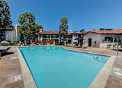 Thumbnail 22 of 57 - Apartments for Rent in Laguna Niguel - Pointe Niguel - Sparkling Pool with Lounge Chairs, Umbrellas, Trees, and View of Apartment Buildings at Pointe Niguel, Laguna Niguel, 92677